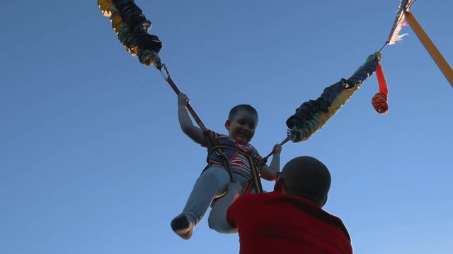 Boy jumping on a trampoline with elastic ropes. Little child jumping on the trampoline. Bungee, jumping.