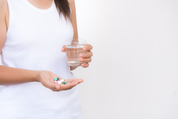 medicine, health care and people concept - close up of woman taking in pill and another hand holding a glass of clean mineral water.