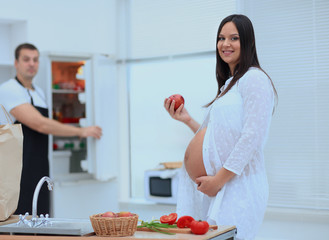 Happy pregnant couple of vegetarians in the kitchen.