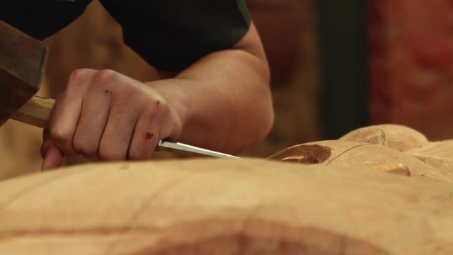 Man carving wood with hammer and chisel