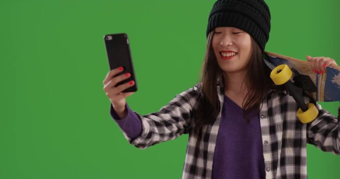 Close up of happy skater taking selfies with skateboard in front of greenscreen