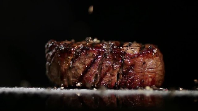 Spices are poured onto the steak and onto the surface.