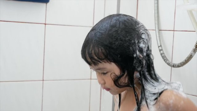 Asian children girl  washing hair in a bathroom, ms shot.