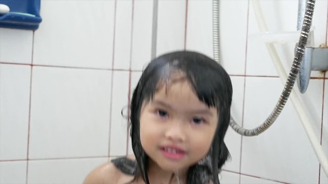 Asian  girl  taking a shower be smile funny and happiness,wet hair taking shower in bath with water indoor, horizontal picture.