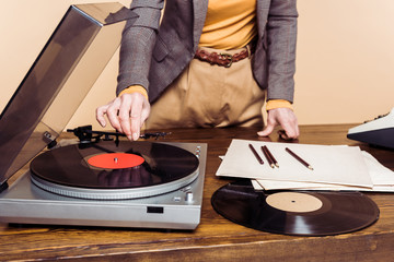cropped image of woman turning on vinyl record player