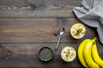 Light fruit dessert for slimming. Banana pudding with superfood chia seeds on dark wooden background with blue tablecloth flat lay copy space