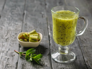 Freshly prepared smoothie of kiwi, Apple, mint and cucumber and kiwi slices on the rustic table.
