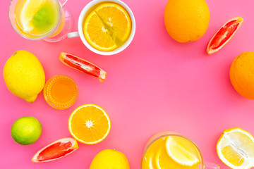 Refreshing summer tea with fruits. Teacup and teapot near orange, lime, lemon, grapefruit on pink background top view space for text