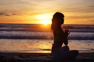 海のサンセットヨガ女性祈り