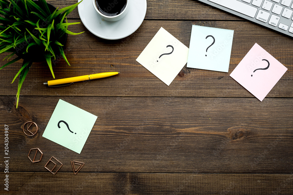 Poster question mark on sticky notes on office desk on dark wooden background top view copy space. faq conc