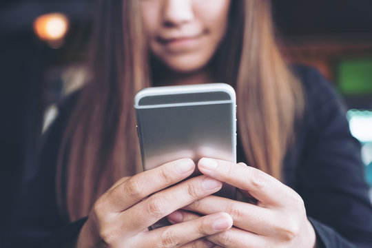 Closeup image of a woman holding , using and looking at smart phone