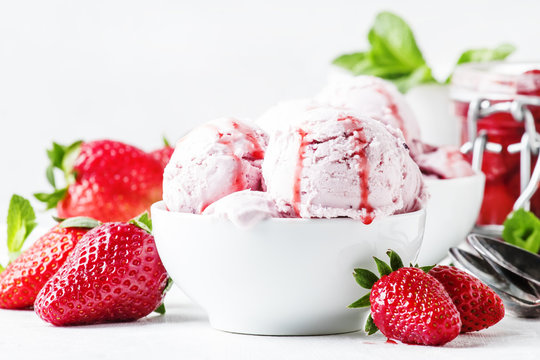 Strawberry ice cream with topping, decorated with mint leaves, white background, high key, selective focus