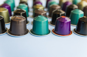 Beautiful colored coffee capsules on light blue background.