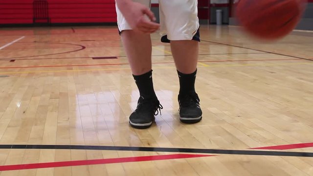 Close up of a basketball going through a hoop in a gym.