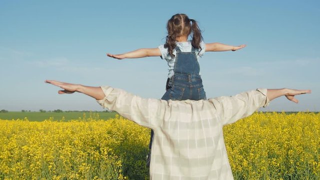 A man is playing with a child on the field. A farmer with a child on a canola field. Father with daughter on the field of rapeseed.
