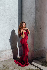 Beautiful young woman in a long red evening gown with a train