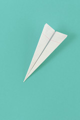 Flat lay white paper plane cell on pastel background top view