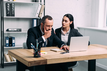 portrait of stressed business people in suits at workplace with laptop in office