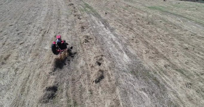 Aerial view of tractor with star wheel rake raking up switchgrass for baling.