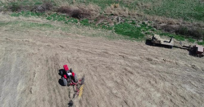 Aerial view straight down of tractor with star wheel rake raking the grass into lines.
