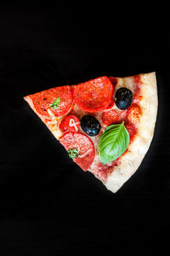 Slices of  Pizza with salami, ham cheese, basil leaf  and bacon, cheese on black chalkboard background, Top view, copy space.
