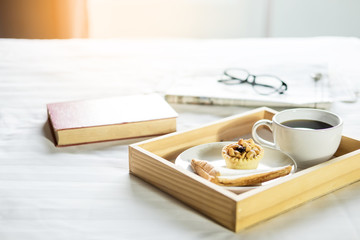 Morning coffee bread and book or newspaper on the bed.
