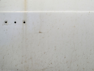 Rust and dents on the body of a white car