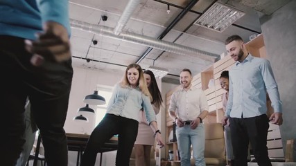 Close-up of male legs playing with football in office, slow motion low angle. Happy colleagues enjoy physical activity. - Powered by Adobe