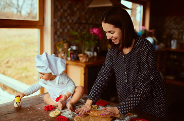 The mother with son knead the dough in the kitchen