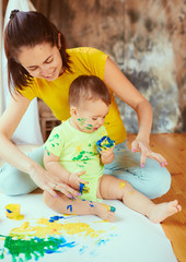 The mother with son painting a big paper by hands