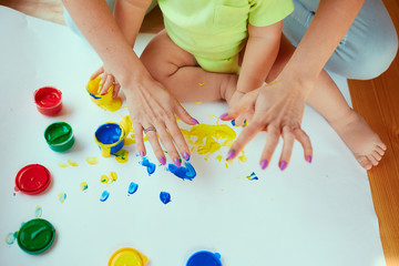 The mother with son painting a big paper by hands