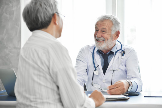 Senior Male Doctor And Asian Male Patient Are Talking.