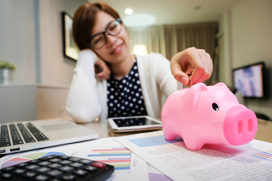 Woman Putting Coin In Pink Piggy Bank.