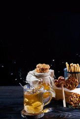 Fototapeta na wymiar A fragrant flower tea with delicious cookies on the dark table
