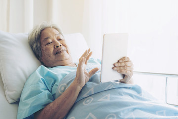 Obraz premium Elderly patients in hospital bed patients using smart phone call to descendant relatives feel happy ness - medical and healthcare concept
