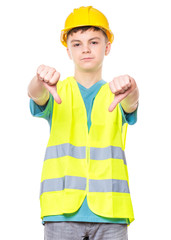 Emotional portrait of handsome child wearing safety jacket and yellow hard hat. Unhappy teen boy giving thumbs down hand gesture and looking at camera, isolated on white background.