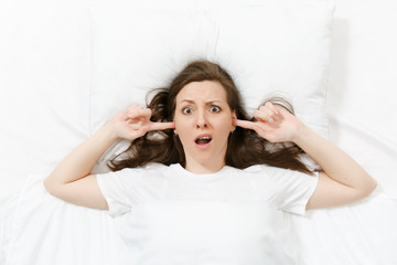 Top view of head of tired brunette young woman lying in bed with white sheet, pillow, blanket....