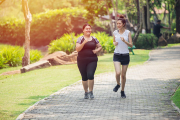 Zwei asiatische Mädchen, dicker und dünner Freund, der im Park joggt