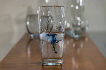 blue ink in water glass on table
