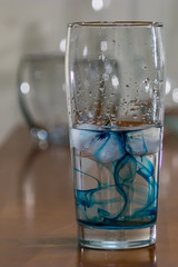 close up of blue ink in water glass on table