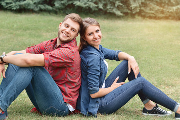 Fototapeta premium Couple siting back in back in the park