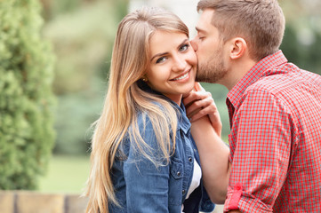 Fototapeta premium Young beautiful girl staring at camera while being kissed