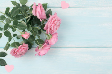 Top view of pink roses with paper hearts on background of shabby wooden planks