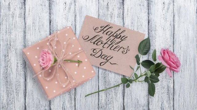 Paper greeting card, gift box and pink rose flower for Mothers day on background of shabby wooden planks