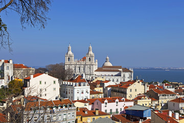 Sao Vicente de Fora Monastery, Alfama District orange rooftops and Tagus River estuary. Lisbon, Portugal.