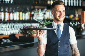 Smiling waiter ready to serve a cocktail - obrazy, fototapety, plakaty