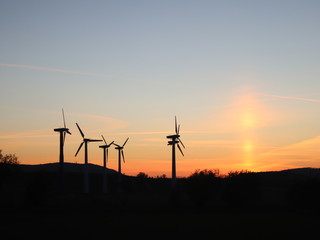 Obraz premium Wind power station in the sunset. Rotating blades of energy generators. Ecologically clean electricity. Modern technologies for the use of natural resources.