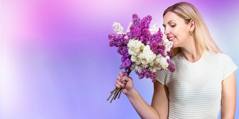 A beautiful young woman inhales the aroma of a spring bouquet of lilac. The concept of the holiday.	