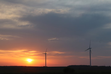 Wind power station in the sunset.  Rotating blades of energy generators. Ecologically clean electricity. Modern technologies for the use of natural resources.