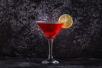 Glass of cosmopolitan cocktail decorated with lime